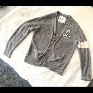 Cardigan sweater medium grey with white trim on sleeves.